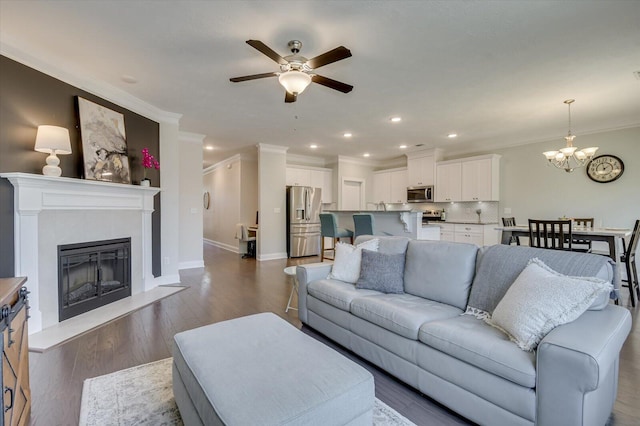 living room with crown molding, ceiling fan with notable chandelier, and dark hardwood / wood-style floors