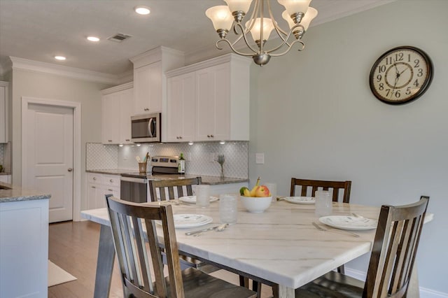 dining space with an inviting chandelier, crown molding, and dark wood-type flooring