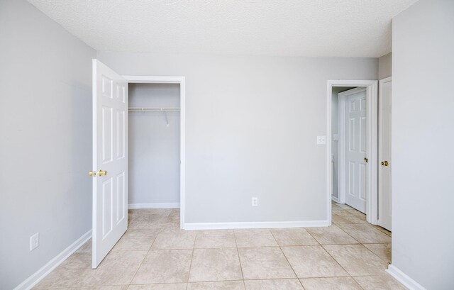 unfurnished bedroom featuring a closet, light tile patterned flooring, and a textured ceiling