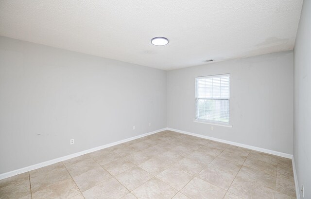 tiled spare room featuring a textured ceiling