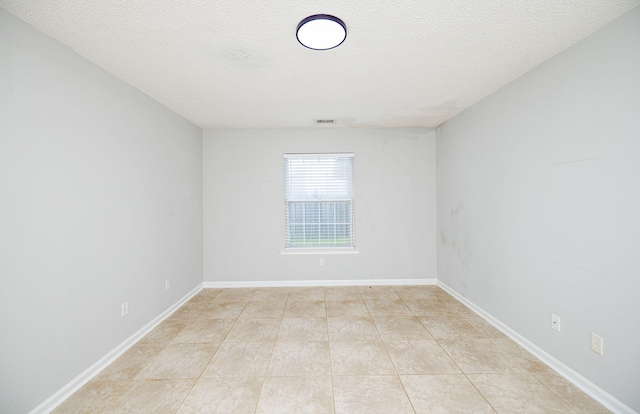 tiled spare room featuring a textured ceiling