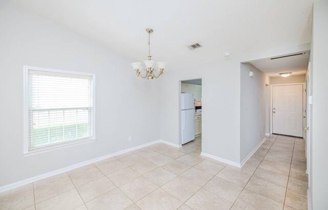 spare room featuring light tile patterned floors, vaulted ceiling, and a notable chandelier