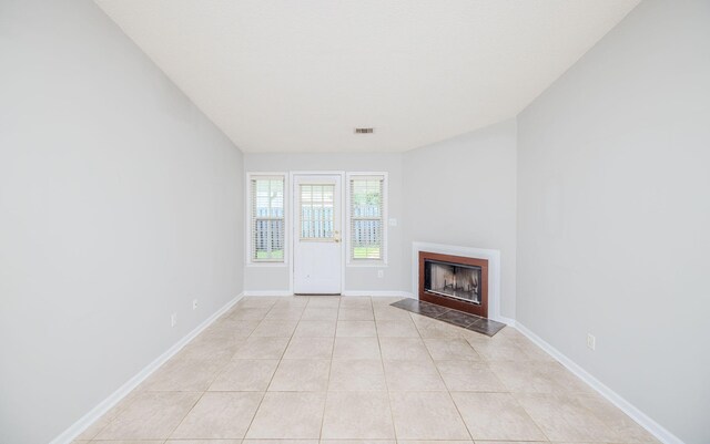 unfurnished living room featuring light tile patterned flooring and a premium fireplace