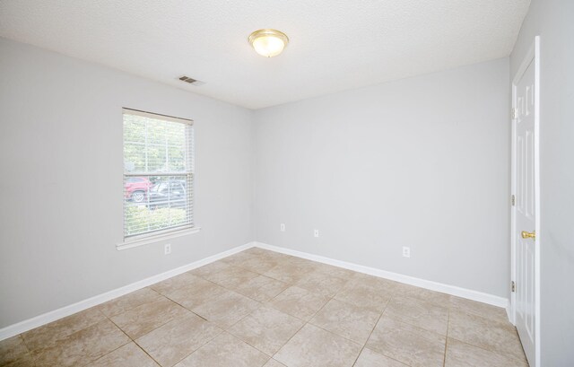 tiled spare room with a textured ceiling