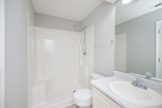 bathroom with vanity, a textured ceiling, toilet, and walk in shower