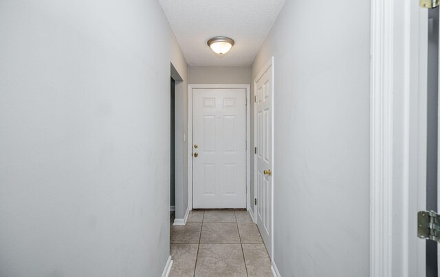 hallway featuring light tile patterned floors and a textured ceiling