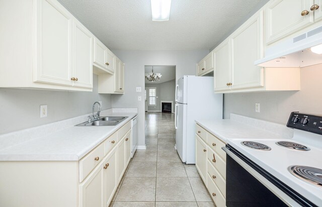 kitchen with white appliances, sink, light tile patterned floors, a notable chandelier, and white cabinetry