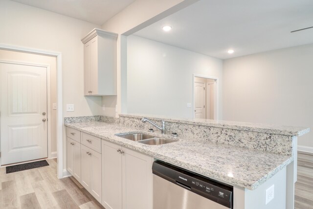 kitchen with sink, light hardwood / wood-style flooring, stainless steel dishwasher, light stone countertops, and white cabinetry