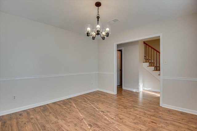 spare room featuring hardwood / wood-style floors and a notable chandelier