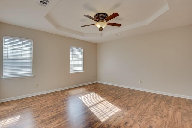 spare room with ceiling fan, wood-type flooring, and a raised ceiling