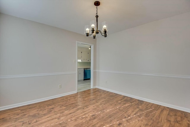 spare room with wood-type flooring and an inviting chandelier