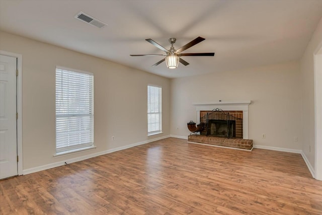 unfurnished living room featuring a brick fireplace, light hardwood / wood-style floors, and ceiling fan