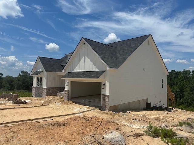 8144 Crossbow Lndg, Graniteville, SC 29829 - view of side of property featuring brick siding, roof with shingles, an attached garage, and board and batten siding