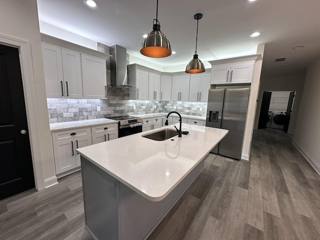 kitchen with light stone countertops, appliances with stainless steel finishes, wall chimney range hood, decorative light fixtures, and independent washer and dryer