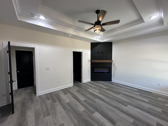 unfurnished living room with ceiling fan, dark hardwood / wood-style flooring, a fireplace, and a tray ceiling