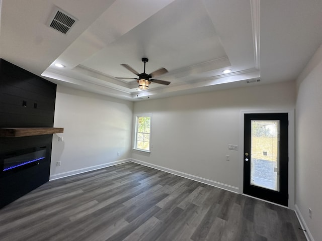 unfurnished living room featuring dark hardwood / wood-style flooring, ceiling fan, a raised ceiling, and crown molding