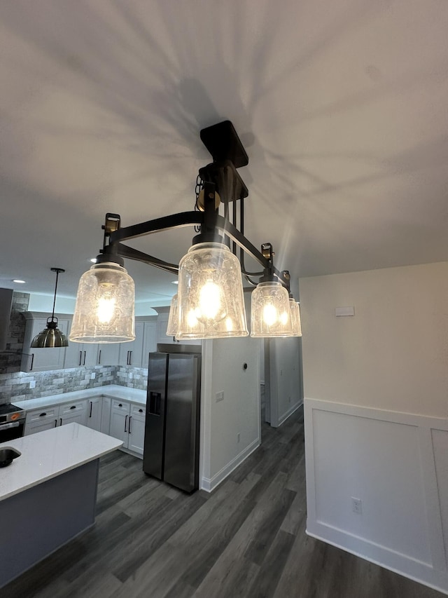 kitchen with dark hardwood / wood-style floors, stainless steel fridge, white cabinetry, and tasteful backsplash