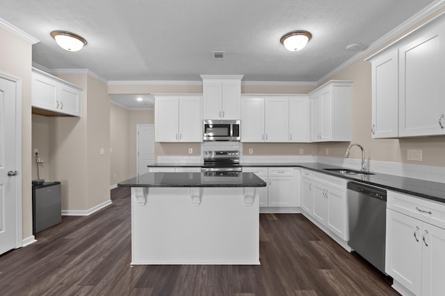 1006 Rosendale Dr, Hephzibah, GA 30815 - kitchen with stainless steel appliances, dark wood-style flooring, white cabinets, a kitchen bar, and ornamental molding