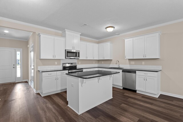 1006 Rosendale Dr, Hephzibah, GA 30815 - kitchen with stainless steel appliances, dark wood-style flooring, white cabinetry, dark countertops, and ornamental molding