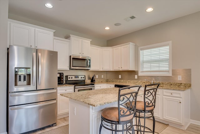 260 Claudia Dr, Grovetown, GA 30813 - kitchen with stainless steel appliances, a kitchen island, white cabinetry, light stone counters, and recessed lighting