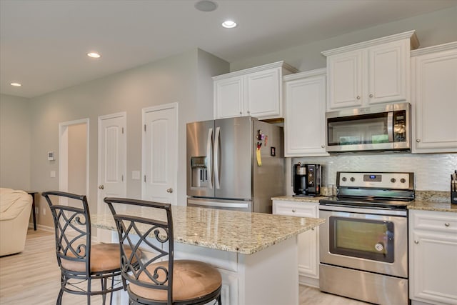 260 Claudia Dr, Grovetown, GA 30813 - kitchen featuring stainless steel appliances, white cabinetry, light wood finished floors, a breakfast bar area, and light stone counters