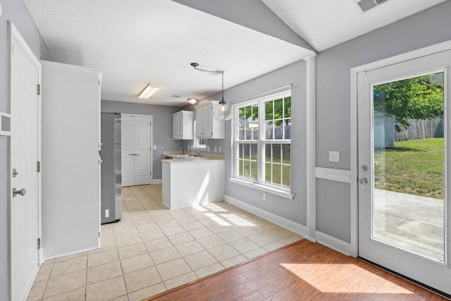kitchen with pendant lighting, refrigerator, light countertops, baseboards, and white cabinetry