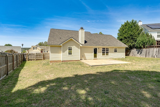 rear view of house with a fenced backyard, a patio area, a yard, and a chimney