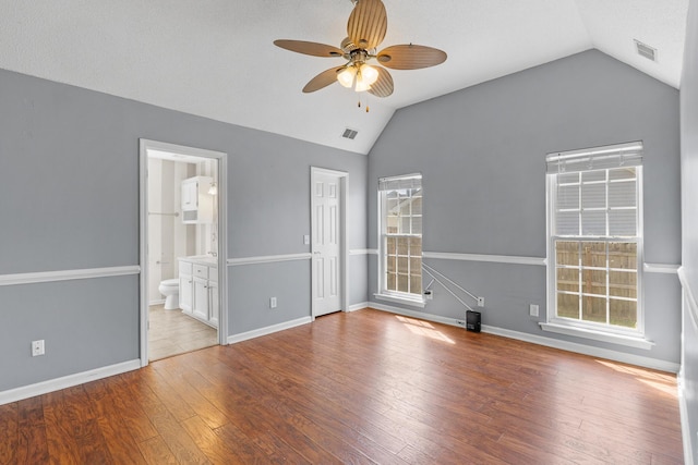 unfurnished bedroom with baseboards, vaulted ceiling, hardwood / wood-style floors, and visible vents