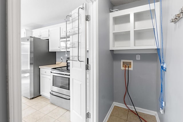kitchen featuring baseboards, light countertops, white cabinets, light tile patterned floors, and stainless steel appliances