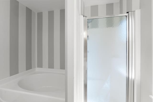 full bathroom featuring a shower stall, wallpapered walls, and a bath