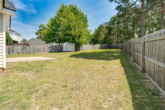 view of yard featuring an outdoor structure, a shed, a fenced backyard, and a patio area