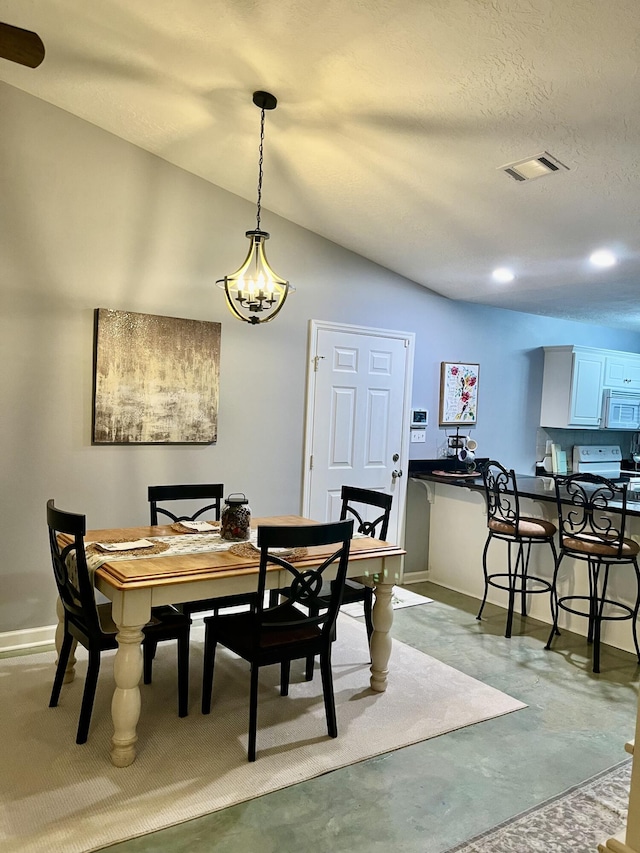 dining space with concrete flooring, visible vents, vaulted ceiling, and baseboards