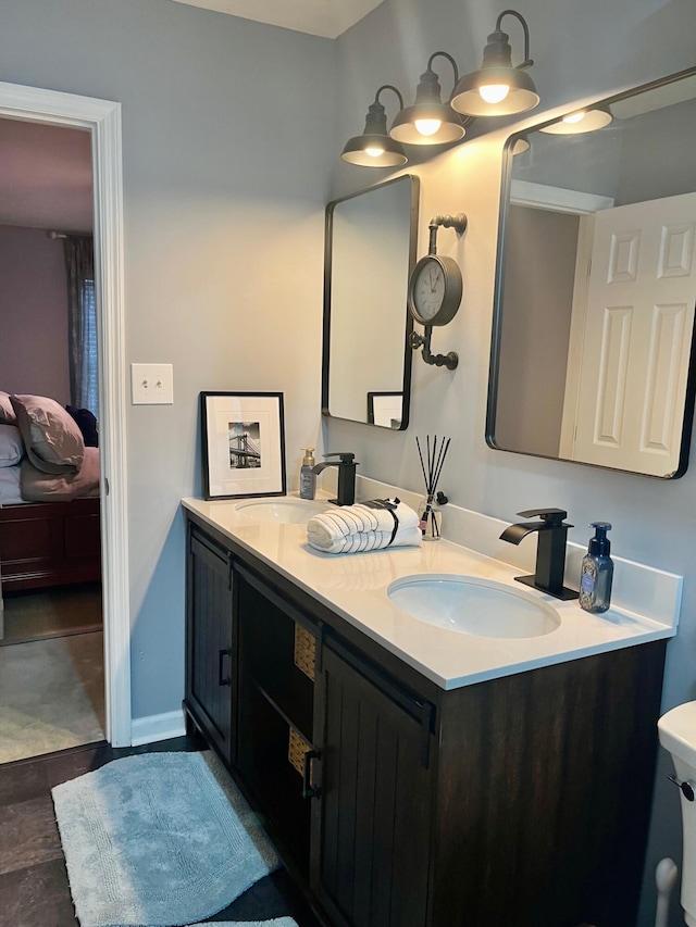 ensuite bathroom with baseboards, a sink, ensuite bath, and double vanity