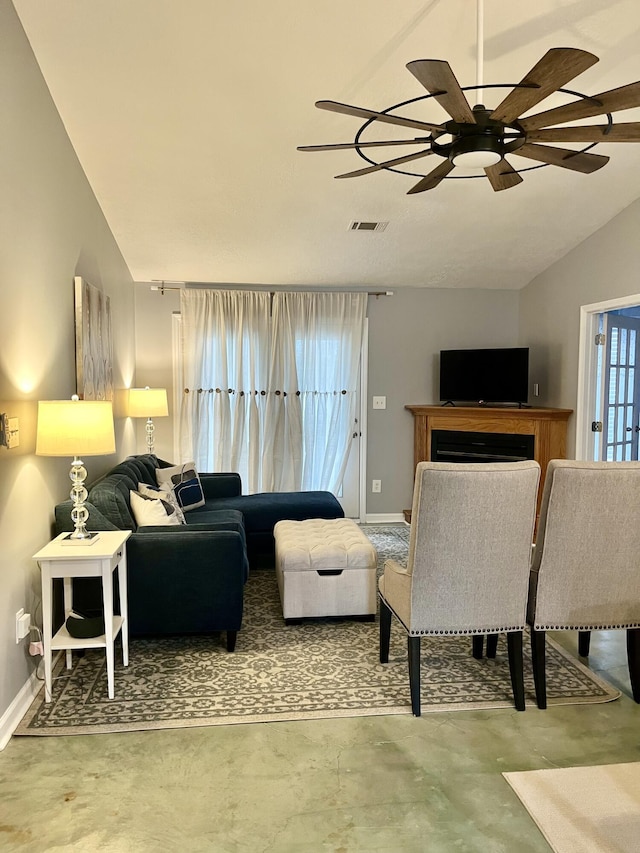 living room with baseboards, visible vents, vaulted ceiling, concrete floors, and a fireplace