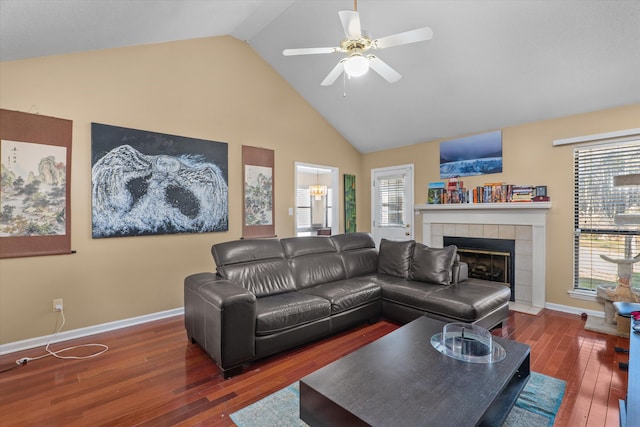 living area featuring hardwood / wood-style floors, a ceiling fan, baseboards, high vaulted ceiling, and a tile fireplace