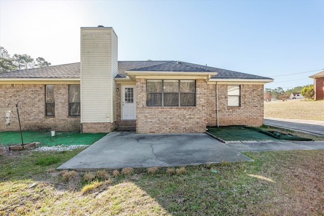 back of property featuring a patio area, a lawn, and roof with shingles