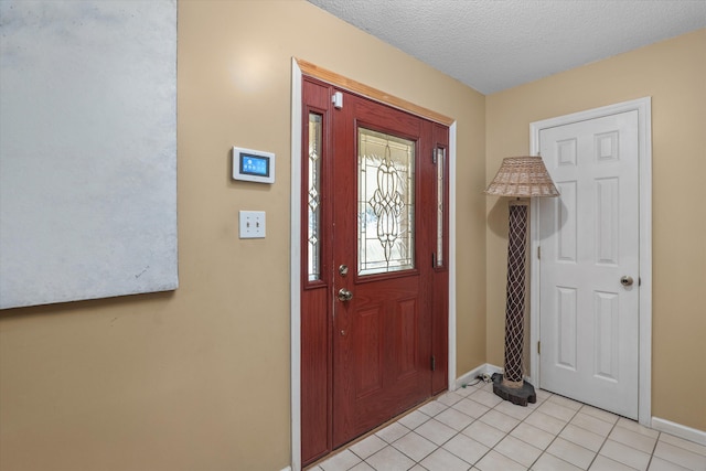 entrance foyer featuring light tile patterned flooring, baseboards, and a textured ceiling