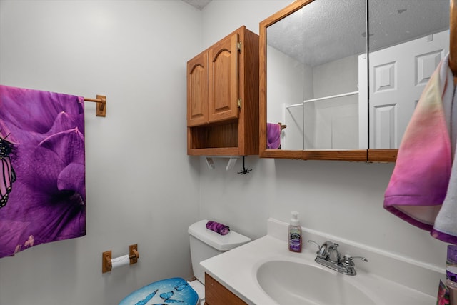 bathroom featuring toilet, walk in shower, vanity, and a textured ceiling