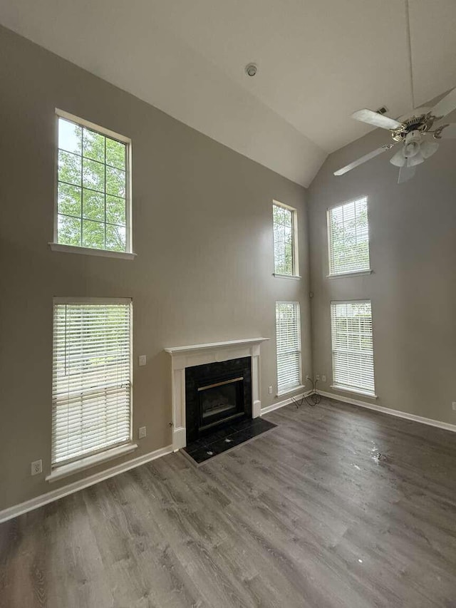 unfurnished living room with high vaulted ceiling, a fireplace, a ceiling fan, wood finished floors, and baseboards