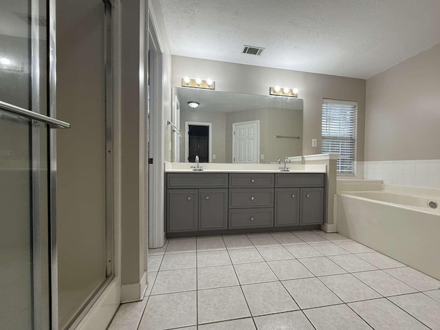 full bathroom with tile patterned floors, a bath, a textured ceiling, double vanity, and an enclosed shower