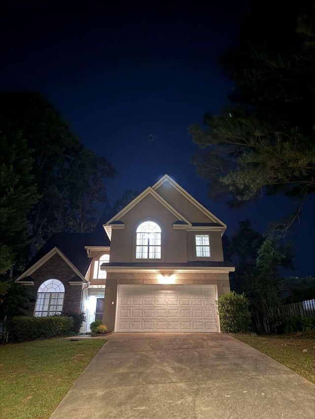 traditional-style home featuring an attached garage, driveway, and stucco siding