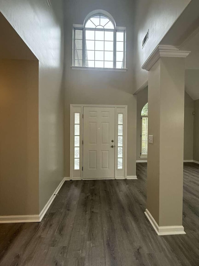 foyer entrance with a high ceiling, dark wood-style flooring, baseboards, and plenty of natural light