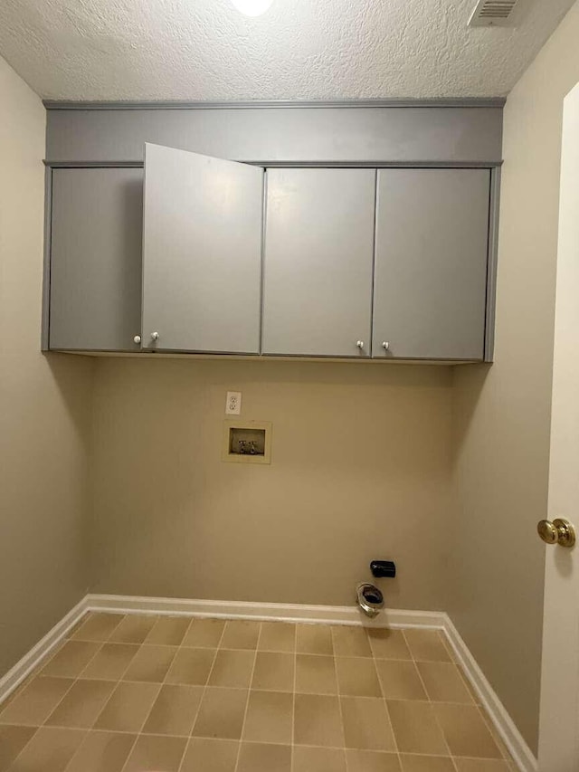 washroom featuring baseboards, cabinet space, washer hookup, and a textured ceiling