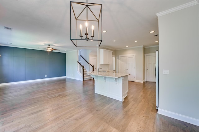 997 Glenhaven Dr, Evans, GA 30809 - kitchen featuring ornamental molding, white cabinetry, a kitchen bar, ceiling fan, and light stone counters