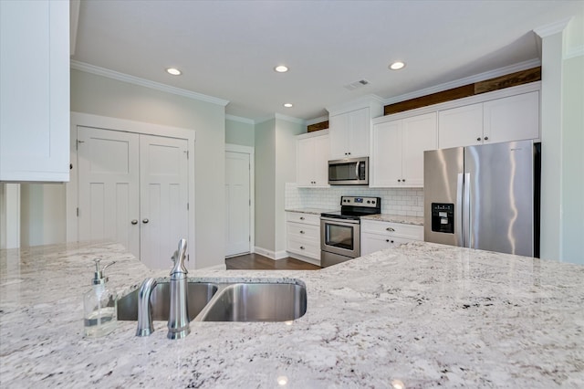 997 Glenhaven Dr, Evans, GA 30809 - kitchen with stainless steel appliances, white cabinetry, light stone counters, crown molding, and backsplash