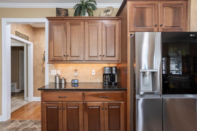 kitchen featuring stainless steel fridge, dark stone countertops, light hardwood / wood-style floors, and crown molding