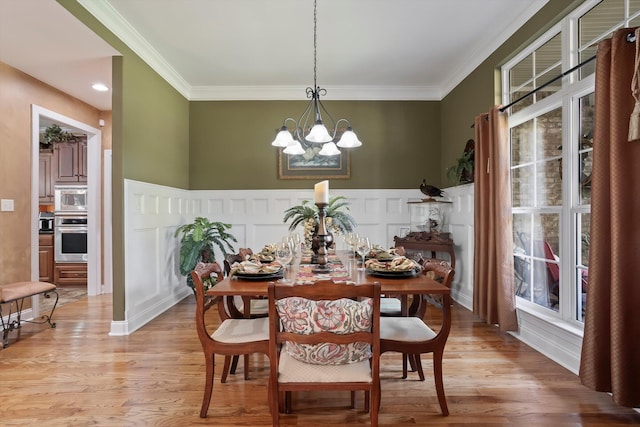 dining space featuring ornamental molding, light wood-type flooring, and a notable chandelier