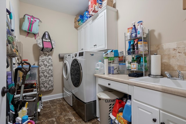 clothes washing area featuring washing machine and dryer, sink, and cabinets