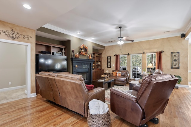 living room with ceiling fan, light hardwood / wood-style floors, crown molding, and built in shelves