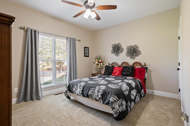 bedroom with multiple windows, ceiling fan, and light carpet